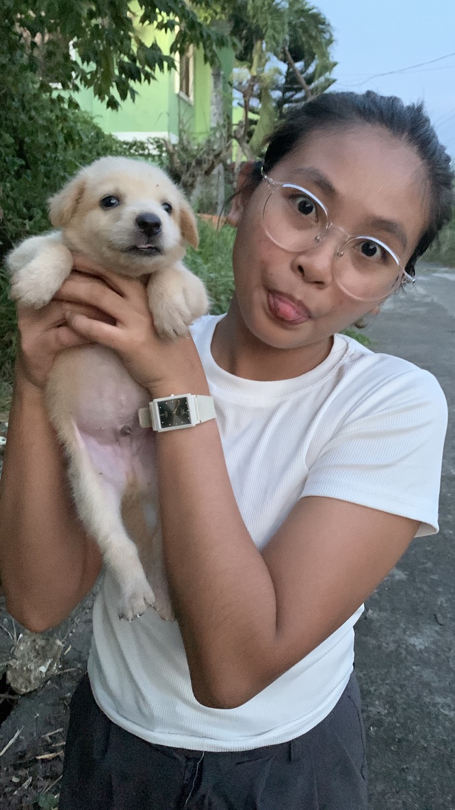 Yolyn holding a cream-coloured puppy at dusk