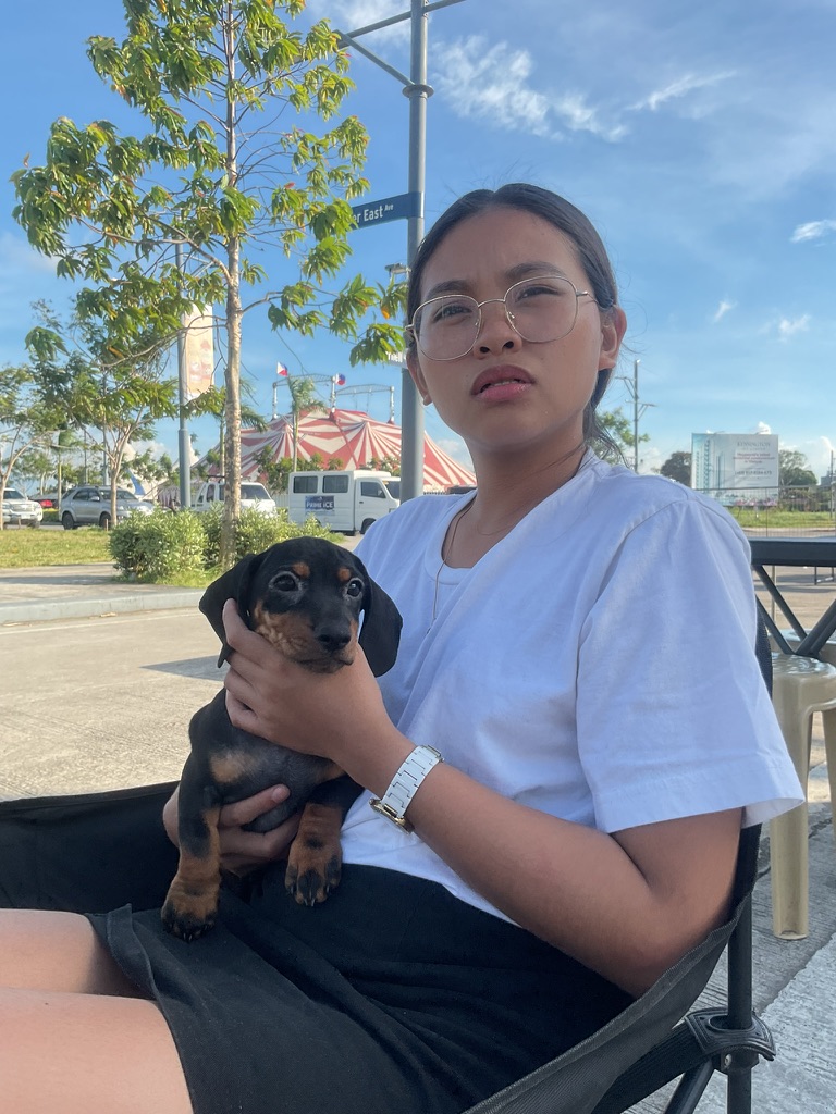 Yolyn holding Aiabells, a black and tan dachshund puppy